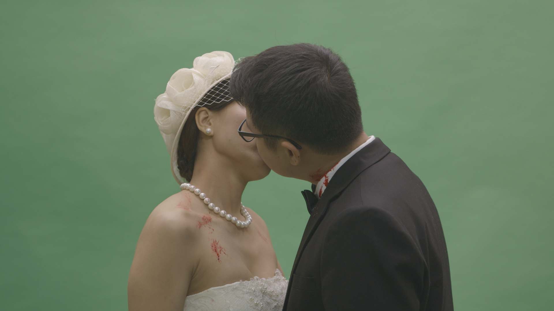 A bridge and groom kiss on green screen.
